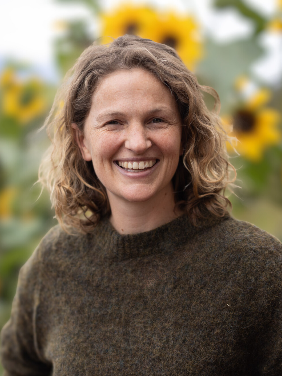 Loo Connor smiling outdoors with greenery in the background.