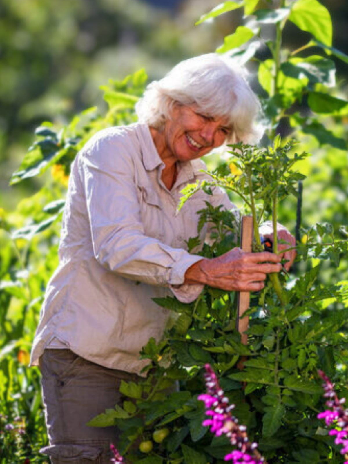 Doris standing in her garden at home, smiling beside her plants.