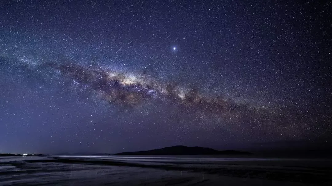 the night sky with stars and an outline of hills